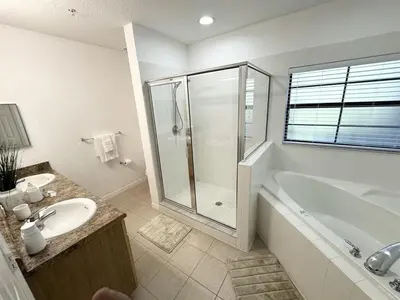 a bathroom with a shower and a tub and a sink at 2BR Condo Close to Disney - Gated, Pool & Hot Tub in Kissimmee