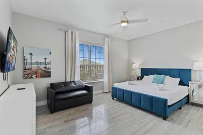 a bedroom with a bed and a black leather chair at Amplo Apartamento 4 Quartos no Vista Cay Resort in Orlando