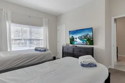 a bedroom with two beds and a flat screen tv at Casa Familiar 10min da Disney + Piscina Privativa in Kissimmee