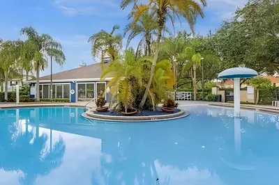 a large pool with palm trees and a building at Casa 3Q Moderna c/ Piscina e Clube Resort in Kissimmee