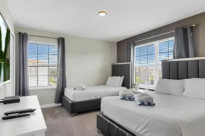 a hotel room with two beds and a desk at Casa 5Q Familiar — 10min da Disney + Piscina in Kissimmee