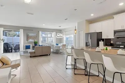 a kitchen and living room with white cabinets and chairs at Casa 5Q Familiar — 10min da Disney + Piscina in Kissimmee