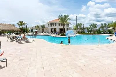 a child holding an umbrella next to a swimming pool at Casa 5Q Familiar — 10min da Disney + Piscina in Kissimmee
