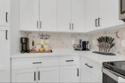 a white kitchen with white cabinets and appliances at Modern 2 Bedrm Apartment with fast Wi-fi - Apartment in Orlando