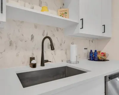 a kitchen with a stainless steel sink and white cabinets at Modern 2 Bedrm Apartment with fast Wi-fi - Apartment in Orlando