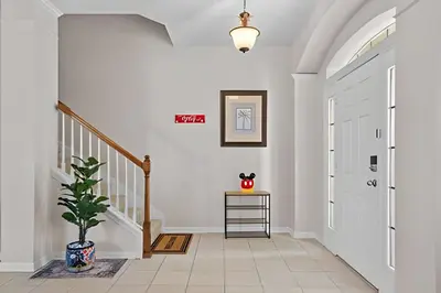 a hallway with white walls and a staircase with a potted plant at Casa 5Q Piscina Resort Windsor Hills Disney in Orlando