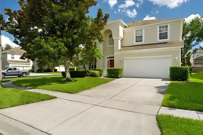 a house with a driveway and a tree at Casa 5Q Piscina Resort Windsor Hills Disney in Orlando