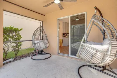a porch with a swinging chair on a balcony at Modern Resort Getaway 9 Mi to Disney Parks! in Kissimmee