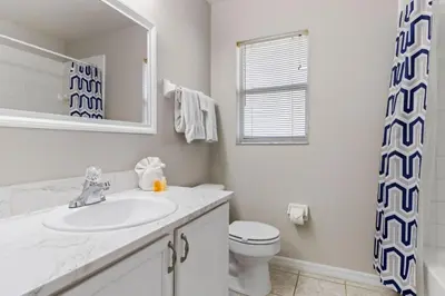 a white bathroom with a sink and a toilet at Orlando Family Retreat 4BR, Private Pool and Lake in Kissimmee