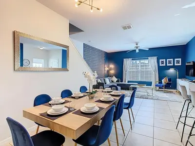 a dining room with a table and blue chairs at Paradise Palms Disney Retreat 5BR Pool Home in Kissimmee