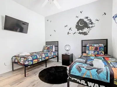 a bedroom with a bed and a tv on the wall at Paradise Palms Disney Retreat 5BR Pool Home in Kissimmee