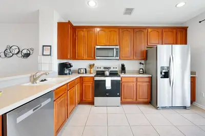 a kitchen with wooden cabinets and a refrigerator at Epic Universe Vacation Townhome, Vista Cay - 4035 in Orlando