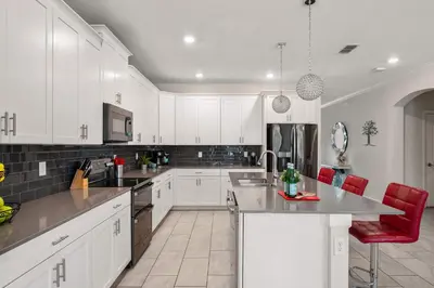 a white kitchen with white cabinets and red chairs at Heated Pool Game Room Waterpark 9MI to Disney in Kissimmee