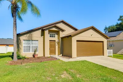 a house with a palm tree and a garage at 10 Mi to Animal Kingdom Clermont Home with Pool! in Orlando