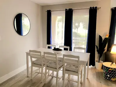 a white dining room table with four chairs and a mirror at Sea World Orlando Apt - Minutes From Parks in Orlando