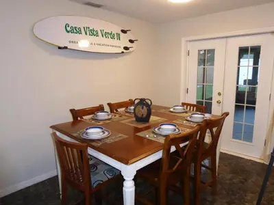 a dining room table with chairs and a surfboard on the wall at Perfecto Mundo 4, Orlando Area 4BR-2BA Jacuzzi-Billiard-Ping Pong-City Pool in Orlando