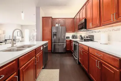 a kitchen with wooden cabinets and a stainless steel refrigerator at The Epic Barcelona Penthouse Vista Cay Orlando Florida in Orlando