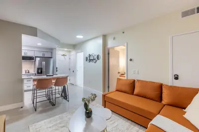 a living room with a couch and a kitchen at Modern Unit w Themed Room, Full Kitchen and Prime Location in Orlando