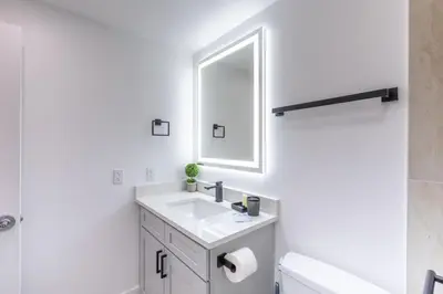 a white bathroom with a sink and a mirror at Modern Unit w Themed Room, Full Kitchen and Prime Location in Orlando
