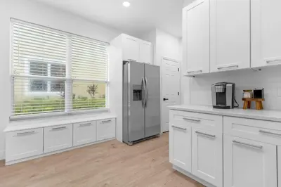 a kitchen with white cabinets and a stainless steel refrigerator at Modern Winter Park Townhome in Prime Location in Orlando