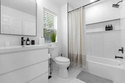 a white bathroom with a toilet and a sink and a shower at Modern Winter Park Townhome in Prime Location in Orlando