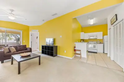 a living room with yellow walls and a couch and a table at 2730 Club Cortile Circle Apt. B in Kissimmee