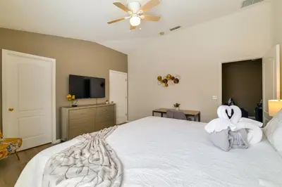 a bedroom with a large white bed with a fan at Peaceful Clermont Gem with Pool, 9 Mi to Disney! in Orlando