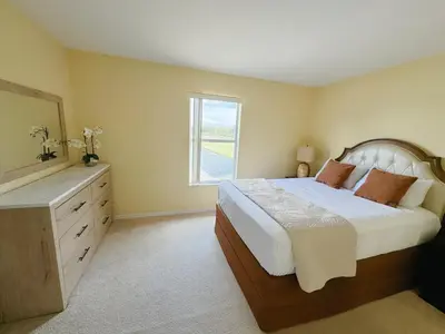 a bedroom with a bed with a dresser and a window at Luxury Family Villa with Pool Near Disney Parks in Kissimmee