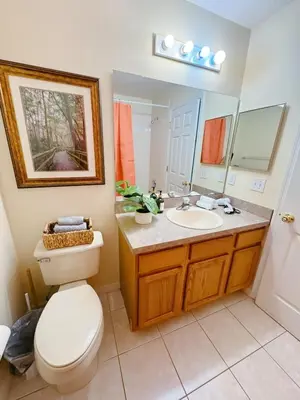 a bathroom with a toilet and a sink and a mirror at Luxury Family Villa with Pool Near Disney Parks in Kissimmee