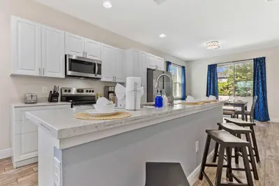a kitchen with white cabinets and a bar with stools at 4461 Summer Flowers Pl in Kissimmee