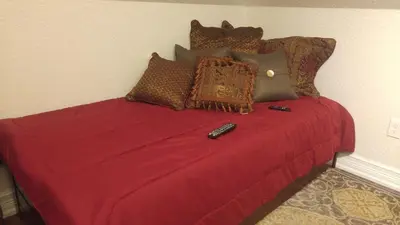 a bed with a red blanket and a remote control on it at Kapp and Kappy Bed & Breakfast in Kissimmee