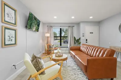 a living room with a brown leather couch and chairs at Modern Escape Near Lake Eola and Downtown Orlando in Orlando