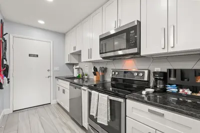 a kitchen with white cabinets and a black stove top oven at Modern Escape Near Lake Eola and Downtown Orlando in Orlando