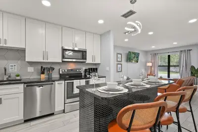 a kitchen with white cabinets and a table with chairs at Modern Escape Near Lake Eola and Downtown Orlando in Orlando
