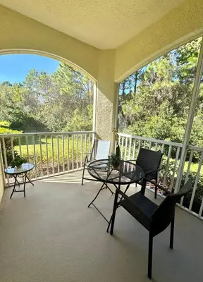 a screened in porch with two chairs and a table at Wonderful apt remodeled in November near Disney in Kissimmee