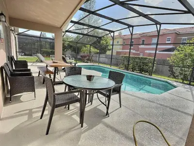 a patio with a table and chairs and a pool at Casa 4Q c/ Piscina Aquecida — Lake Berkley in Kissimmee