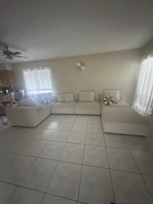 a living room with two white couches and two windows at Maxx Maximum Comfort LLC in Orlando