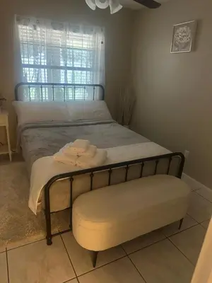 a bedroom with a bed with a bench and a window at Maxx Maximum Comfort LLC in Orlando