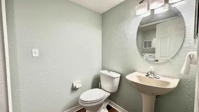 a bathroom with a toilet and a sink and a mirror at Park Hopper Paradise At Regal Oaks in Orlando
