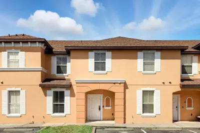 a large orange house with white shuttered windows at Park Hopper Paradise At Regal Oaks in Orlando