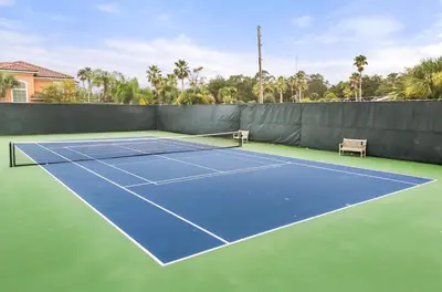 a tennis court with two chairs on it at Park Hopper Paradise At Regal Oaks in Orlando