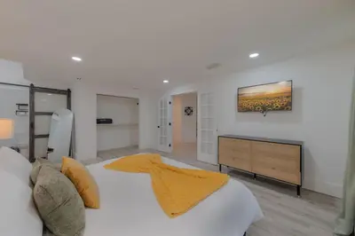 a white bedroom with a large bed and a dresser at Entire Home with Pool, Ping Pong Table and Arcade games in Kissimmee