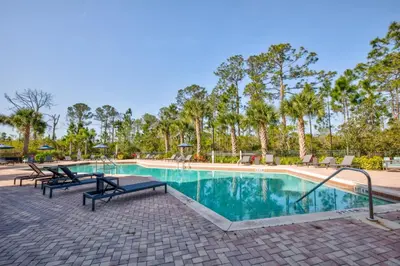 a swimming pool at a resort with benches and trees at Upstay Pet Friendly Condo 6 Minutes from Disney in Orlando