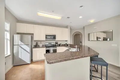 a kitchen with white cabinets and a granite counter top at Upstay Pet Friendly Condo 6 Minutes from Disney in Orlando