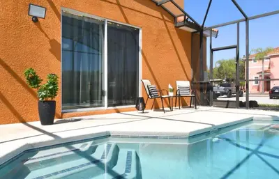 two chairs and a swimming pool in front of a building at Family Home 20 min Disney 4BR Heated Pool BBQ in Kissimmee