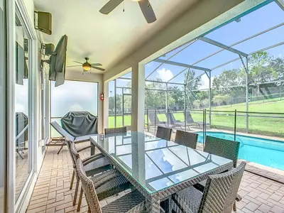 a patio with a glass table and chairs and a pool at 4BR Luxury Villa, Pool & GameRoom in Windsor Hills in Orlando