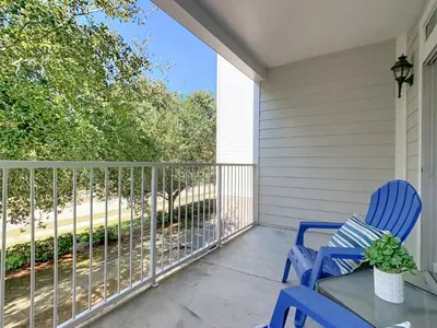a porch with two blue chairs and a table at Themed 2BR Condo Near Disney + Resort Amenities in Kissimmee