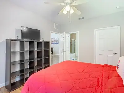 a bedroom with a red bed and a ceiling fan at Themed 2BR Condo Near Disney + Resort Amenities in Kissimmee