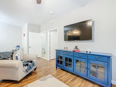 a living room with a blue cabinet and a tv on a wall at Themed 2BR Condo Near Disney + Resort Amenities in Kissimmee