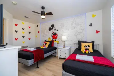 a bedroom with two beds and a wall with disney characters at Cozy 4 BR close to Disney in Kissimmee